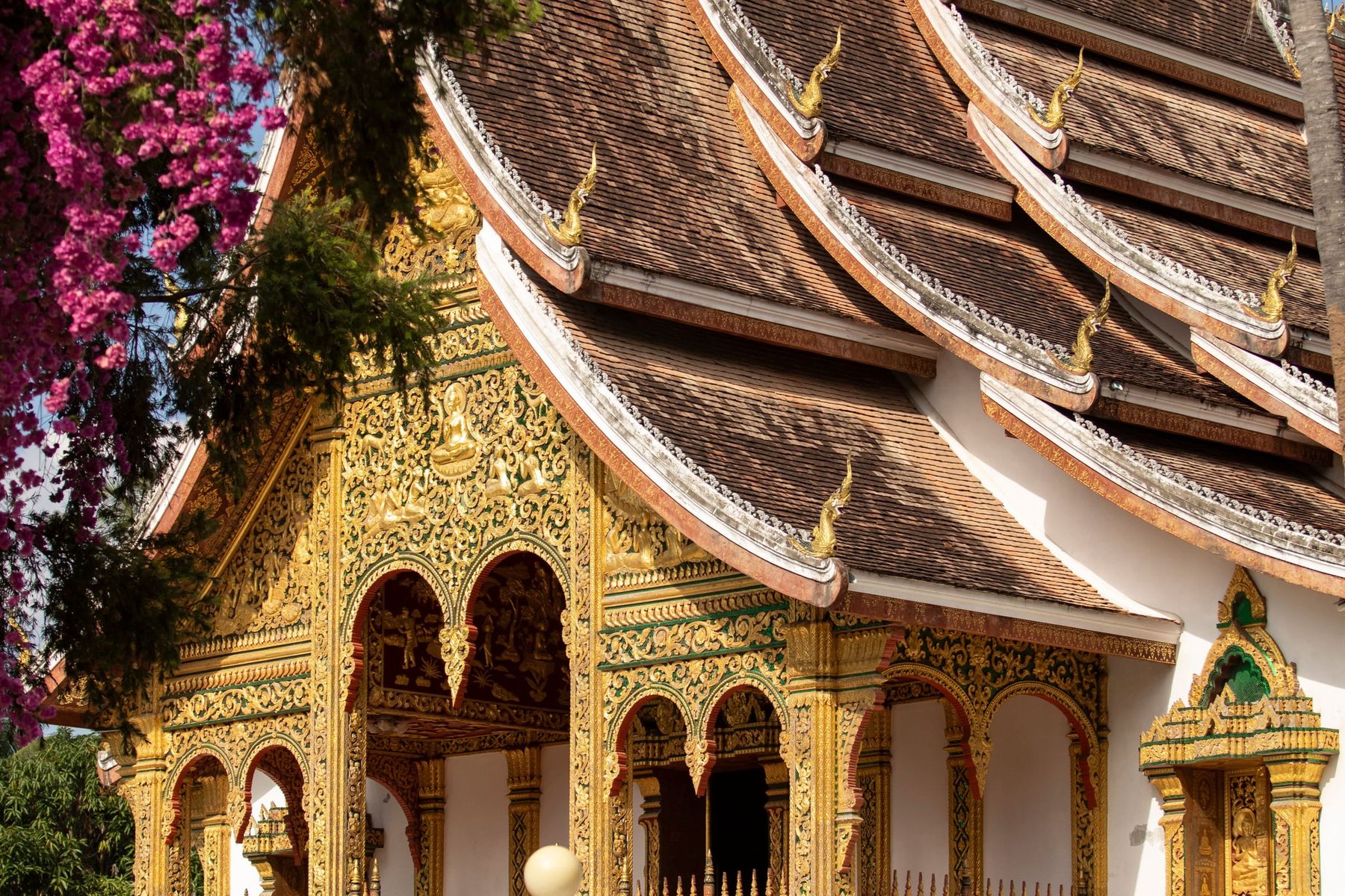 The gilded facade and layered roof of a temple in Luang Prabang, Laos