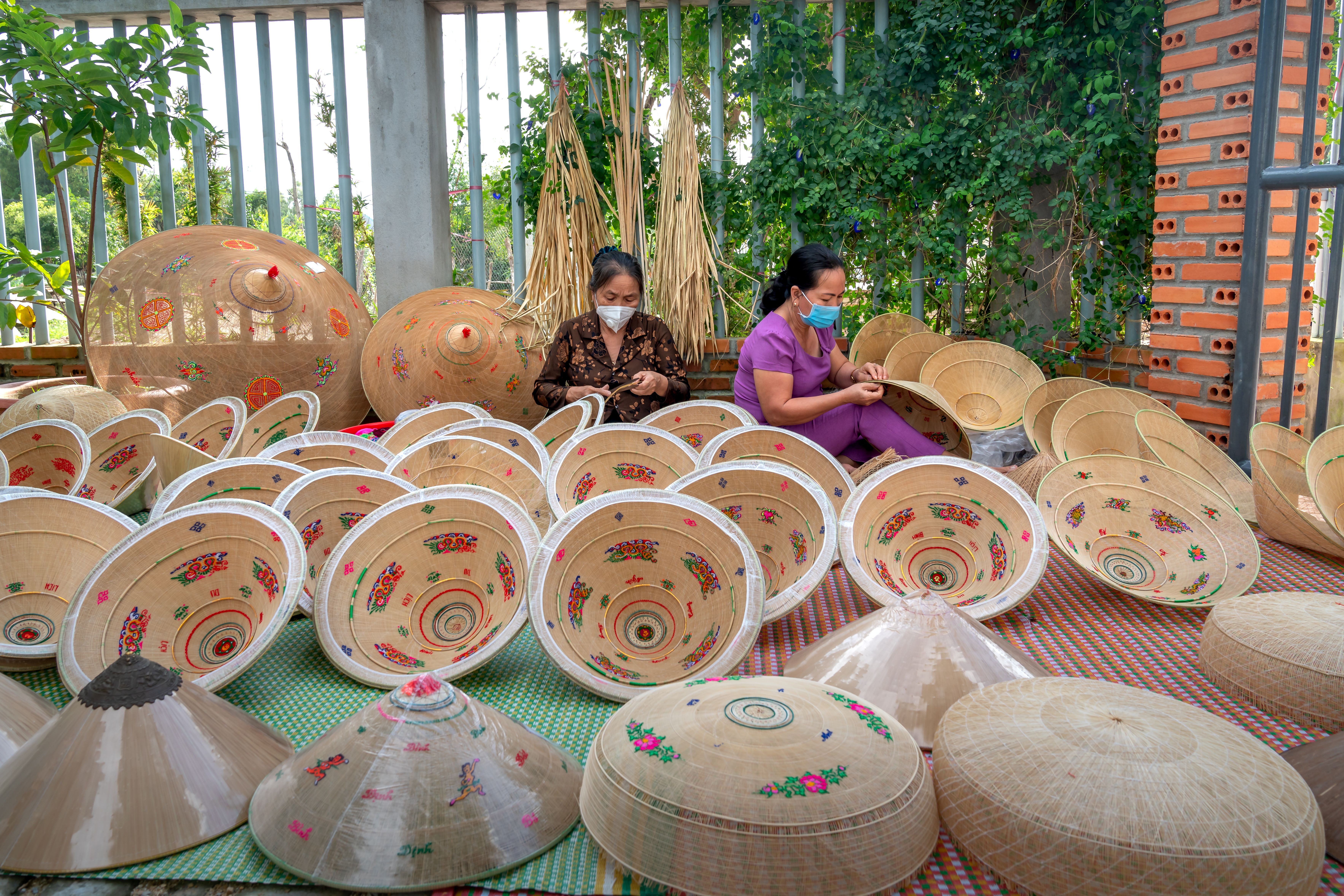 A woman shaping the frame of a conical hat in the countryside near Hue