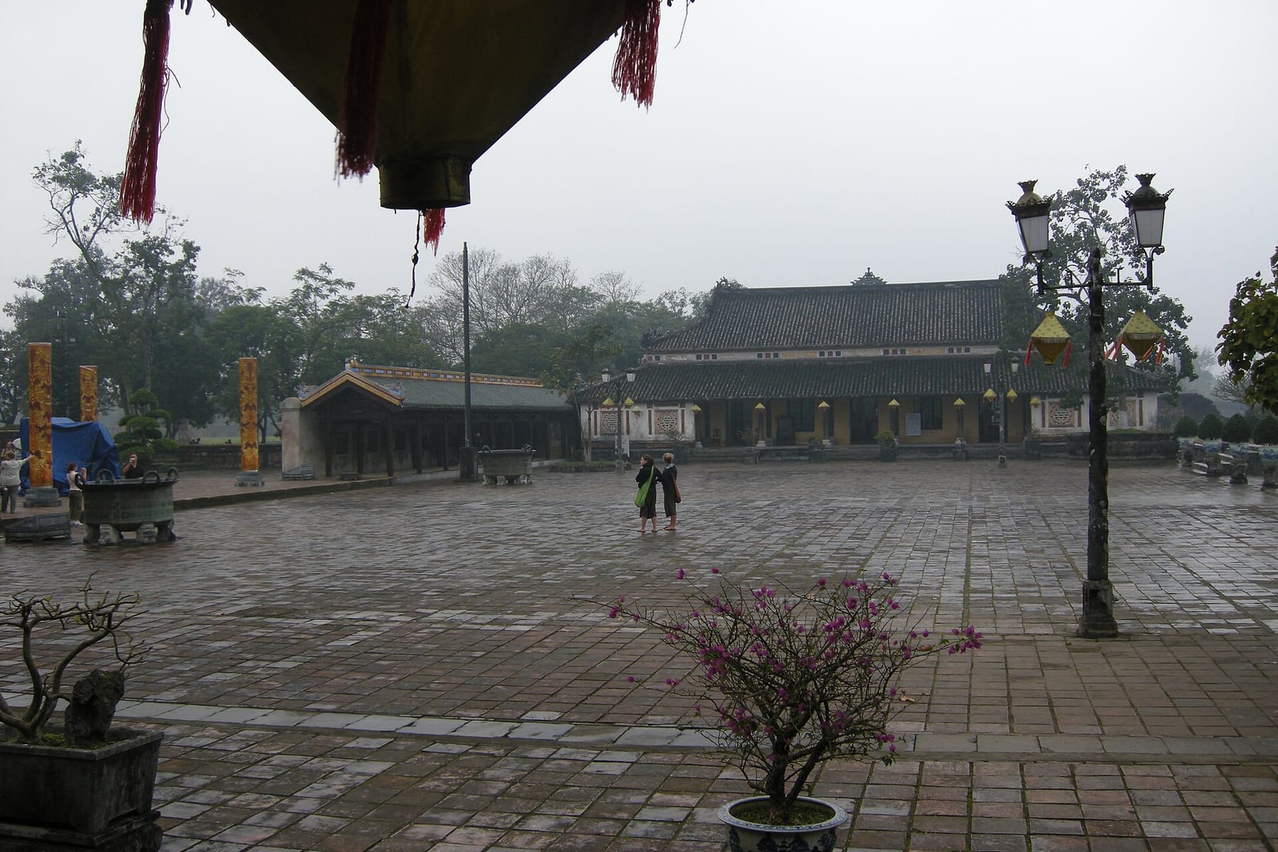 Two visitors crossing an almost empty courtyard inside the Imperial City at Hue